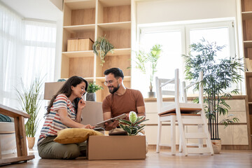 Happy couple unpacking cardboard boxes and furnishing new home