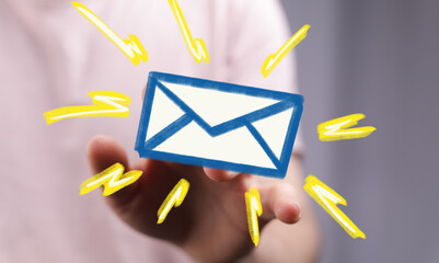 Hand holding a digital email icon with bright yellow lighting effects.  Perfect for communication...
