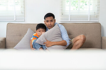 Family Bonding and Fun. Father and son enjoying a thrilling movie moment on the couch.