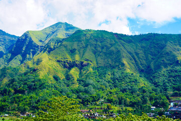 Panoramic view of green landscape with mountains, blue sky and white clouds from Selong Hill, Sembalun, Lombok, West Nusa Tenggara, Indonesia.