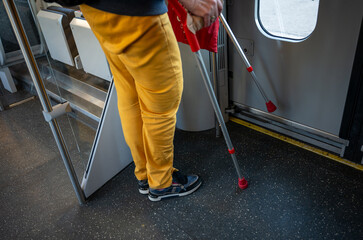 Person with crutches standing inside public transportation, showing accessibility and mobility aid