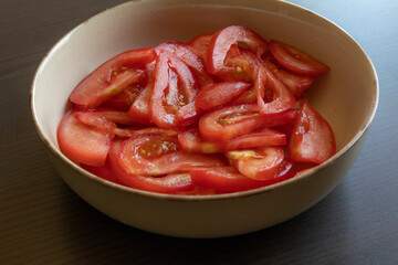 Close-up photo of fresh tomato slices in a white bowl