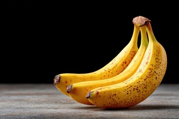 Bananas arranged on a dark surface showcasing their vibrant yellow color and unique speckled texture