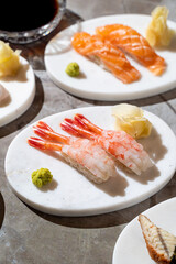 Delicate sushi artfully arranged on sleek plates showcases fresh shrimp and salmon, garnished with vibrant wasabi and ginger, creating a culinary masterpiece at sunset