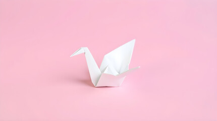 White origami crane resting on pink background symbolizing peace and hope