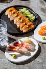 Delight in an artistic arrangement of sushi showcasing glistening salmon, delicate shrimp, and colorful accompaniments, all served in a stylish dining setting