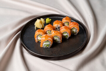 A beautiful arrangement of sushi rolls features fresh salmon slices, crisp cucumbers, and savory fillings atop a dark plate, highlighted by vibrant wasabi and ginger