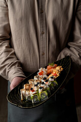 A skilled chef presents an artfully arranged platter of sushi. Fresh ingredients and vivid colors highlight each roll, inviting diners to savor a unique culinary experience in a serene atmosphere