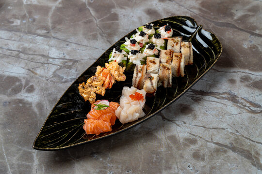 A beautiful assortment of sushi and sashimi presented on an elegant leaf-shaped platter