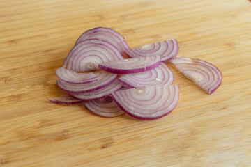 Close-up photo of slices of red onion on a wooden board