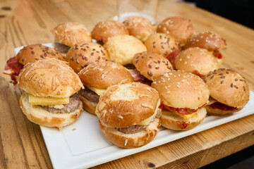 Mini burgers with cheese and bacon filling a white tray