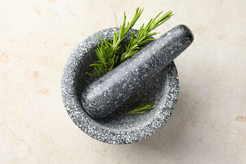 Stone mortar with rosemary and pestle on light table, top view