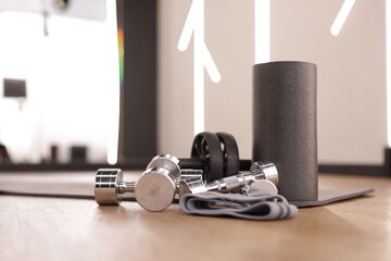 Dumbbells, elastic band, foam roller and mat on floor in fitness studio