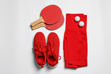 Sportswear, sneakers, ping pong rackets and balls on white background, flat lay