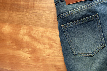 Jeans pants on the table wood background. back pocket of blue jeans, denim texture.
