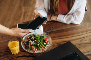 Top close up view. Woman is paying for meal by wireless payment in the cafe restaurant