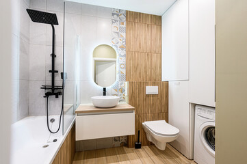 Modern bathroom with wood accents, white fixtures, black shower, and a round mirror