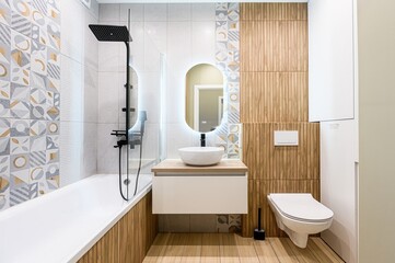 Modern bathroom with geometric tiles, wood panels, and a sleek sink vanity. Features a bathtub with...