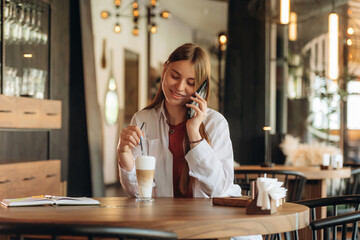 Conversation by phone, talking. Young woman is in the cafe at daytime