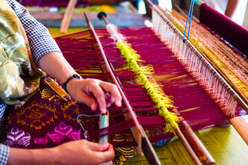 An Indonesian woman making Songket cloth with traditional tools at Sukarara village, Lombok, West Nusa Tenggara, Indonesia.