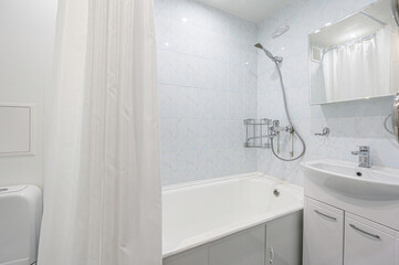 Clean bathroom with tub, shower, sink and mirror. White and light blue tones
