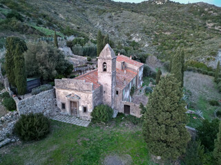 Fototapeta premium Abandoned stone church with a bell tower surrounded by woodland, Elba, Italy