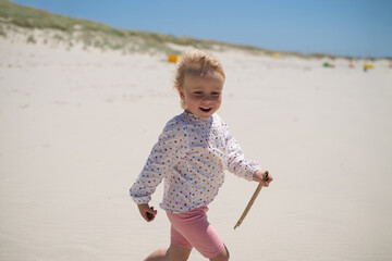 Little Girl Playing Alone in the Sand on the Beach