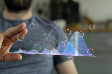 Stock photo of a man interacting with a holographic display showing data charts and graphs.
