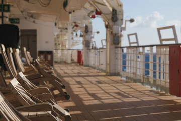 Obraz premium Outdoor promenade boat sun deck onboard modern luxury cruiseship cruise ship ocean liner with teak wood loungers and deck chairs for guests passengers with ocean views