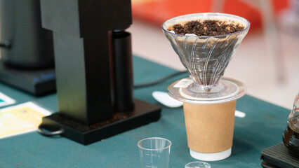 A coffee brewing setup featuring a funnel, filter, and cup on a table, showcasing the process of making fresh coffee.