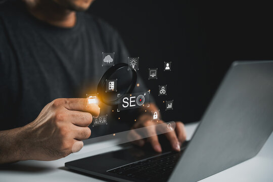 Person Using Magnifying Glass on SEO Concept Graphics while Working on Laptop with Dark Background to Illustrate Digital Marketing Techniques and Outreach Strategies