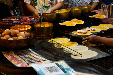 Traditional local thai food dessert Khanom bueang crispy pancake or thai crepes snack with variety sweets topping for people travelers select buy eat drink at street market bazaar in Bangkok, Thailand