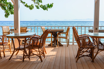 Cozy seaside terrace with wooden furniture and stunning ocean view during sunny daytime