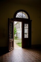 Open vintage wooden door revealing courtyard with old building outside view