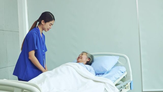 Female nurse cares for an elderly patient diabetes who is resting in a bed by covering her with a blanket to keep her warm during her recovery in the hospital.
