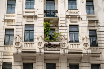 Ornate building facade with classical architectural details and small balcony garden
