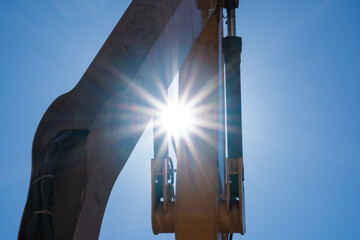 Looking up at an exavator arm against the blue sky