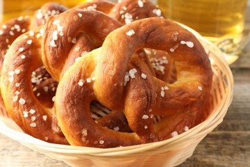 Tasty pretzels in basket on wooden table, closeup