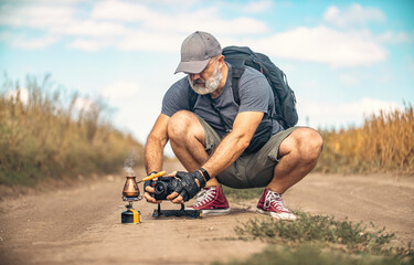 Male photographer crouched down and holding camera in middle of field road. Taking pictures of...