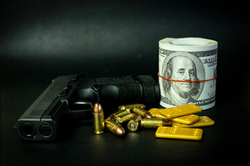 Gun bullets and a roll of money paper currency on a black background with a feeling of danger and crime