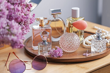 Bottles of perfumes, accessories and lilac flowers on wooden table