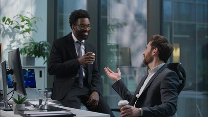African American coworker giving cup coffee for Caucasian male businessmen business men colleagues buddies talking smiling friends pause relaxing drinking break guys in office workers chatting laugh
