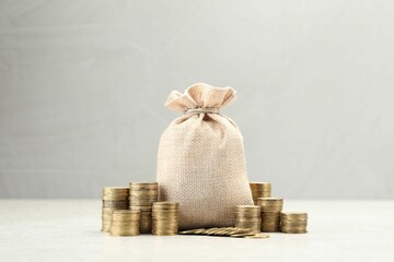 Bag and stacked coins on white table. Space for text
