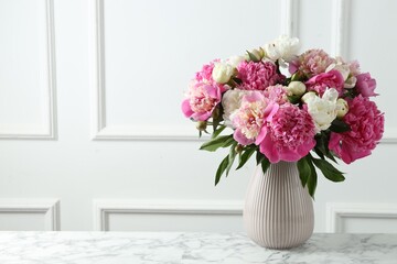 Bouquet of beautiful peonies in vase on white marble table indoors, space for text