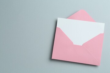 Blank invitation card and envelope on grey background, top view. Space for text