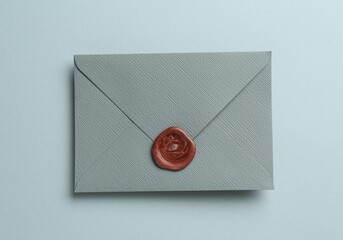 Beautiful invitation envelope with wax seal on grey background, top view