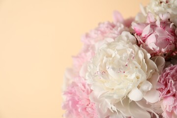 Bouquet of beautiful peonies on beige background, closeup. Space for text