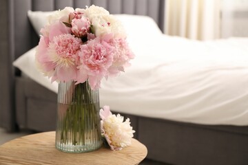 Beautiful peonies in vase on wooden table indoors. Space for text