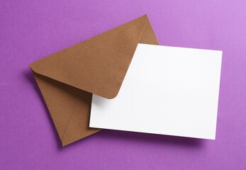 Blank invitation card and envelope on purple background, top view. Space for design