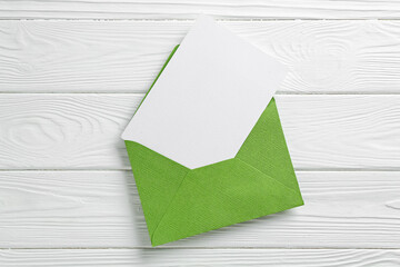Blank invitation card and envelope on white wooden table, top view. Space for design